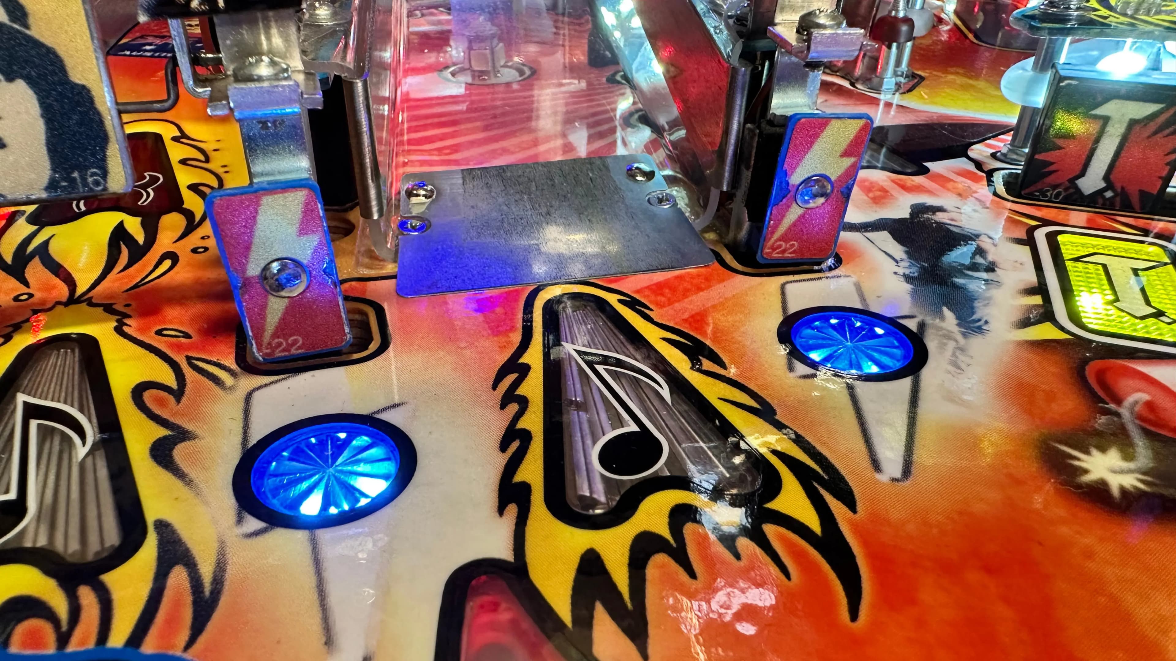 Colorful pinball machine with blue-lit targets and vibrant artistic design