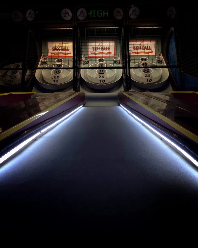 Vintage skee-ball arcade game with illuminated scoring boards and lanes