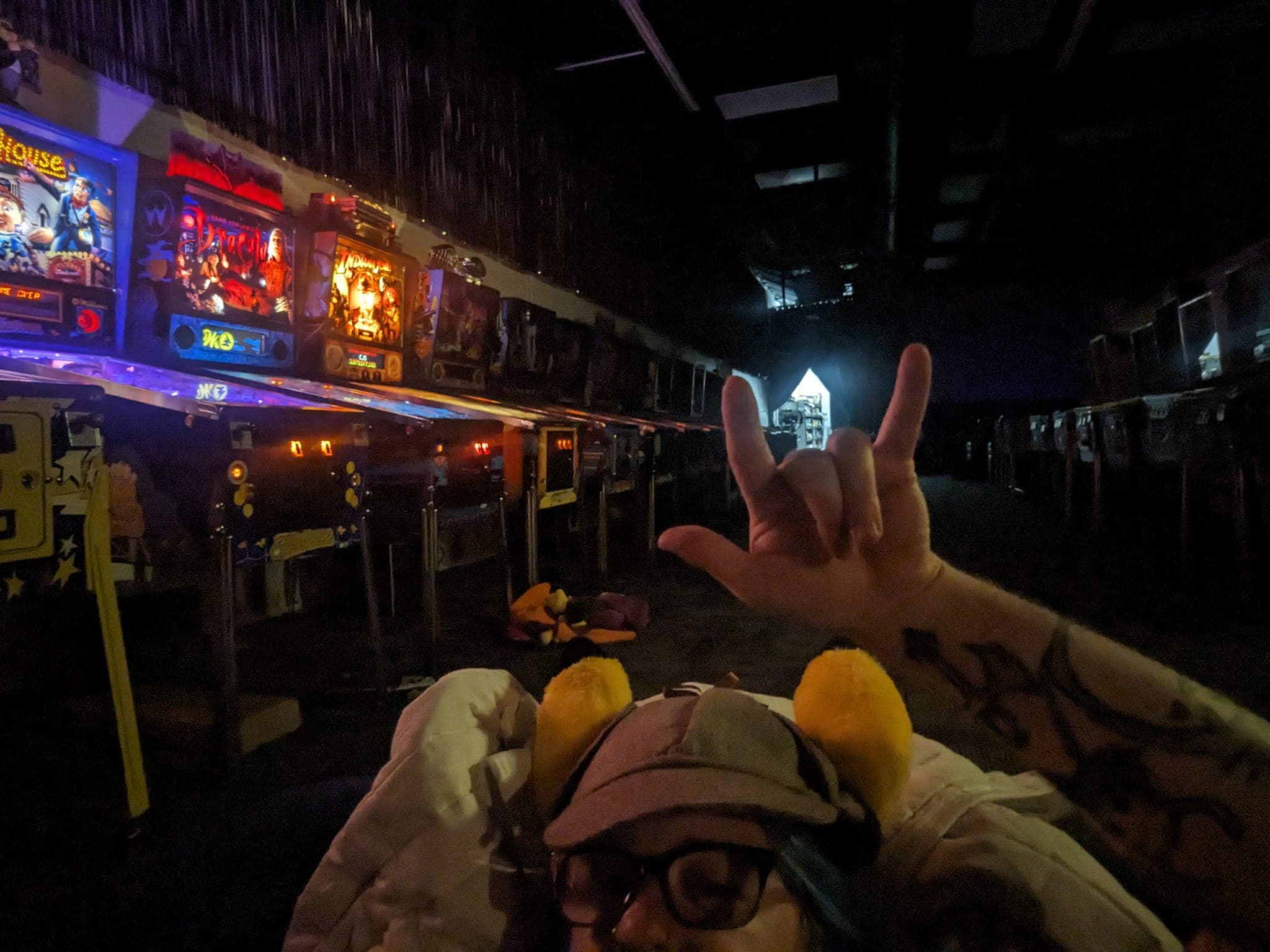 Arcade scene at night with colorful game screens and rock hand gesture