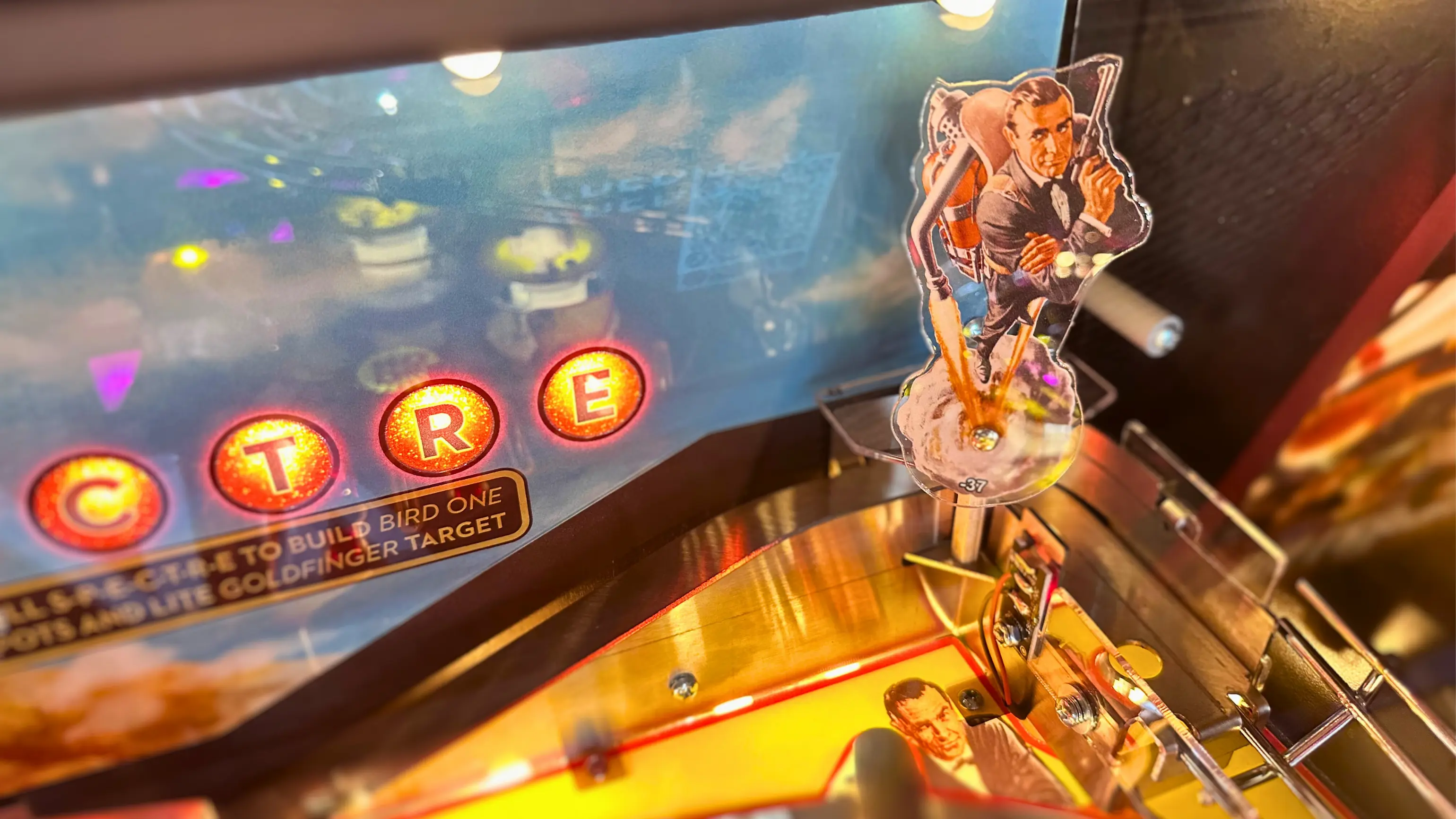 Vintage pinball machine with glowing letters and James Bond figurine