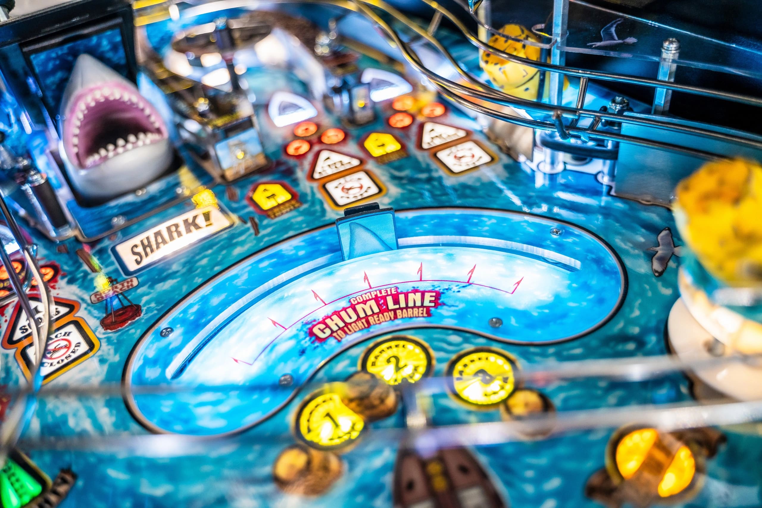 Shark-themed pinball machine with blue water background and yellow buttons