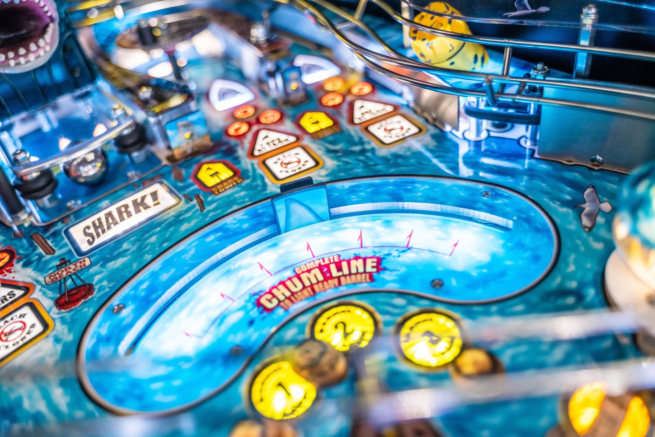 Close-up of a shark-themed pinball machine with blue background