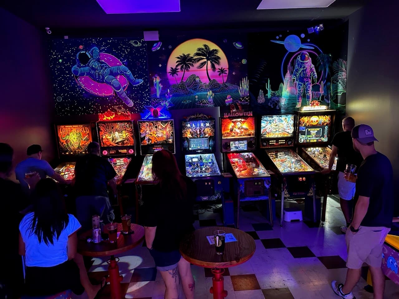 Colorful arcade with retro pinball machines and space-themed murals