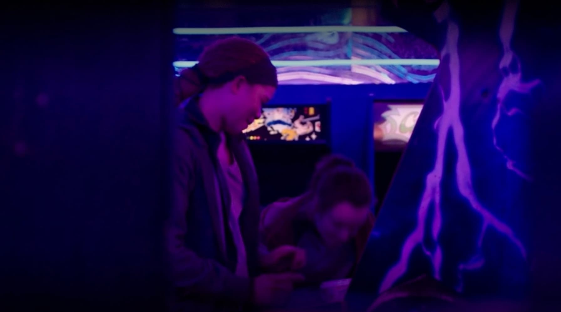 People gathered around screens in dark, purple-lit gaming or tech environment