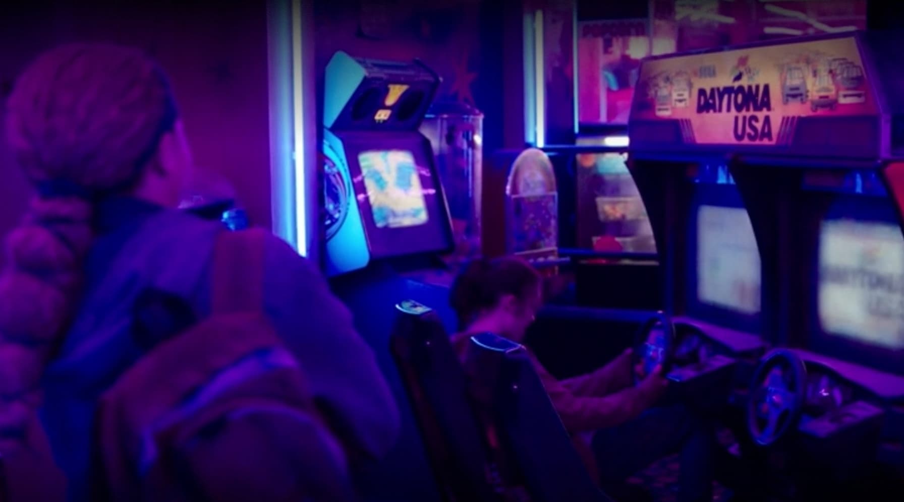 Arcade racing game with Daytona USA cabinet in neon-lit retro gaming room