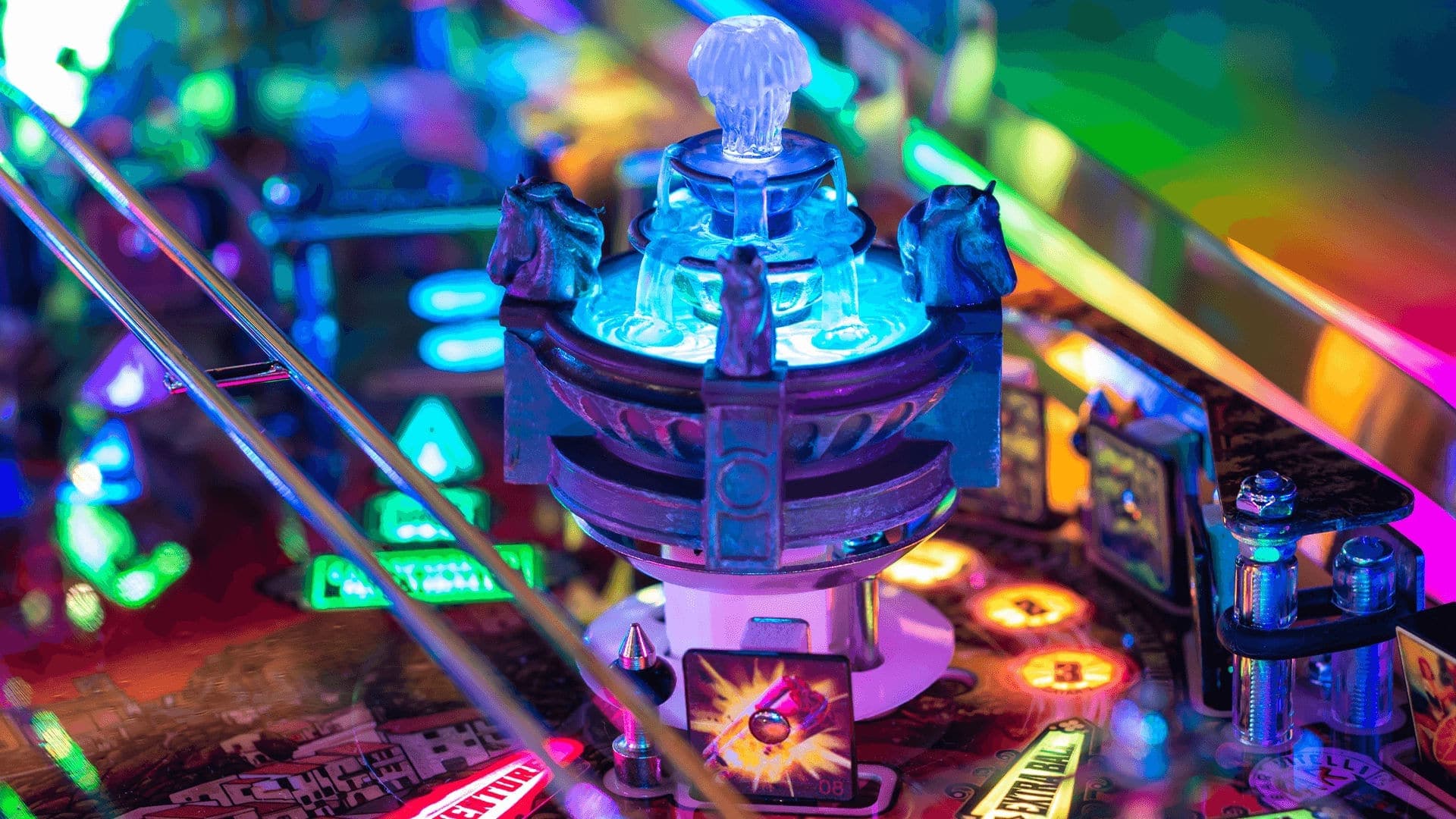 Colorful pinball machine detail with glowing blue central mechanism and lights