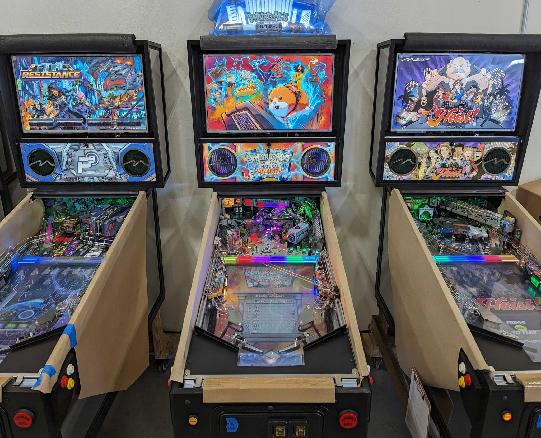 Three colorful pinball machines with unique artwork and playfields