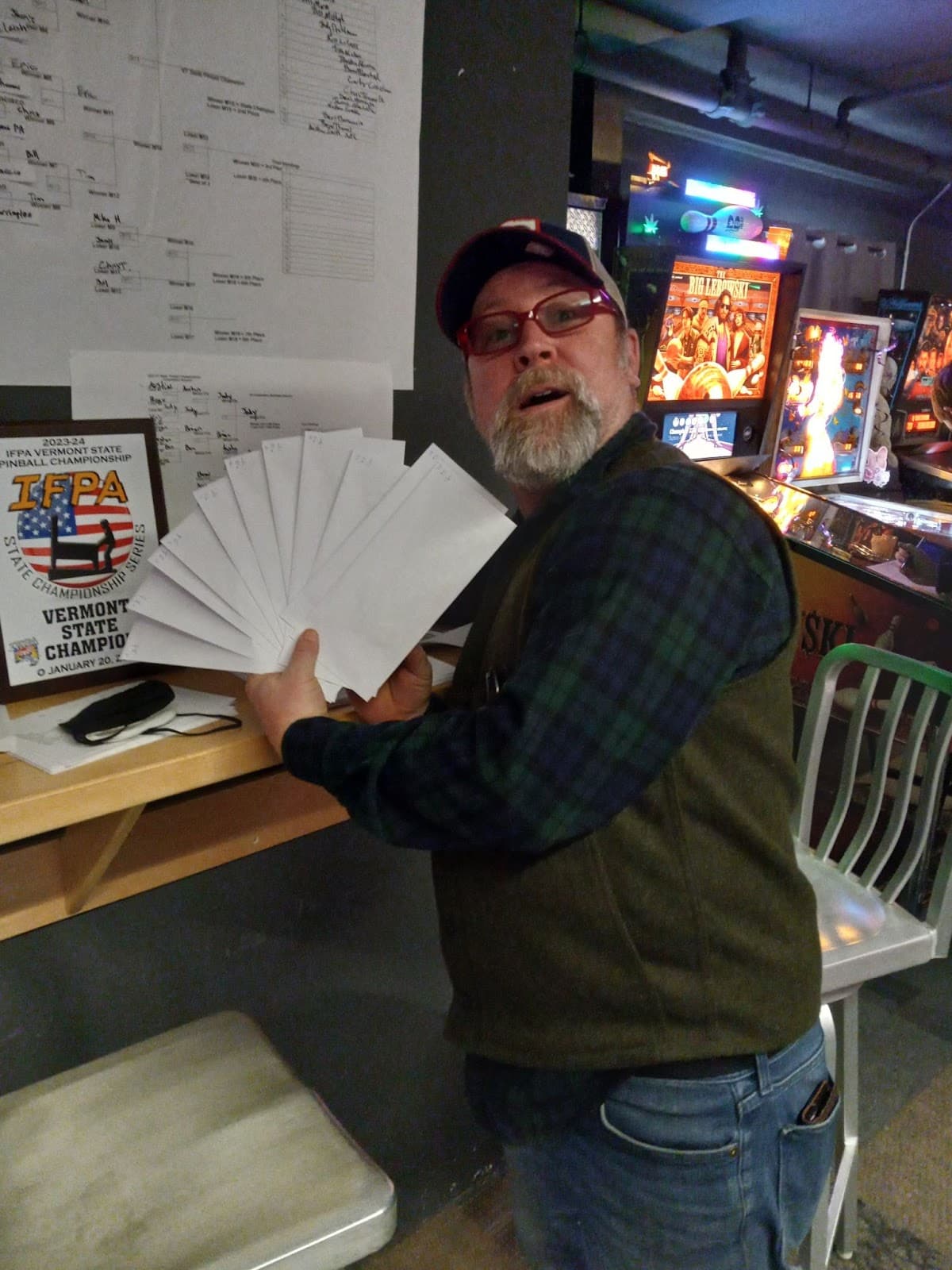 Pinball enthusiast displays Vermont State Championship certificates near arcade machines