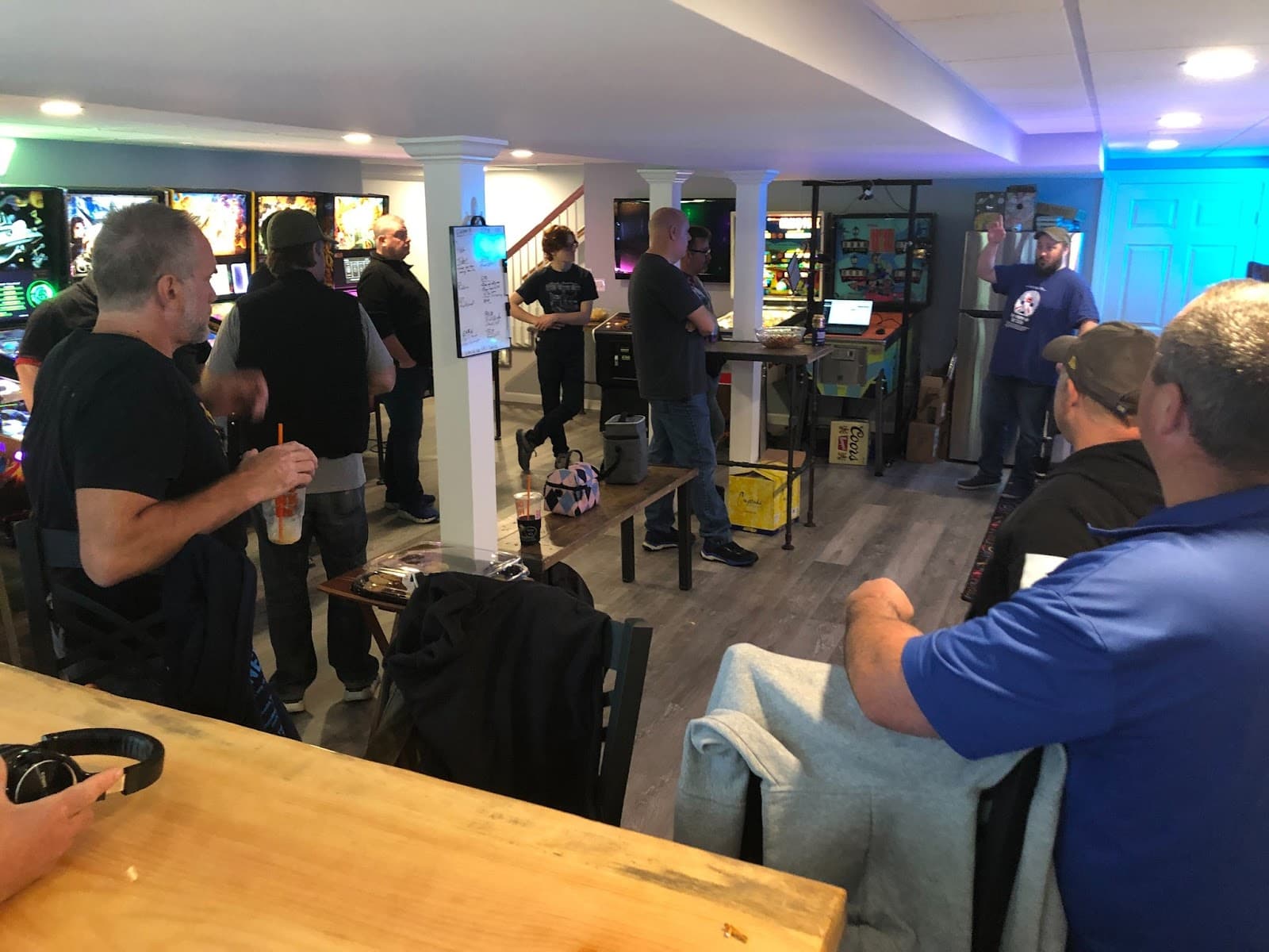 People gathered in a modern game room with colorful lighting and screens