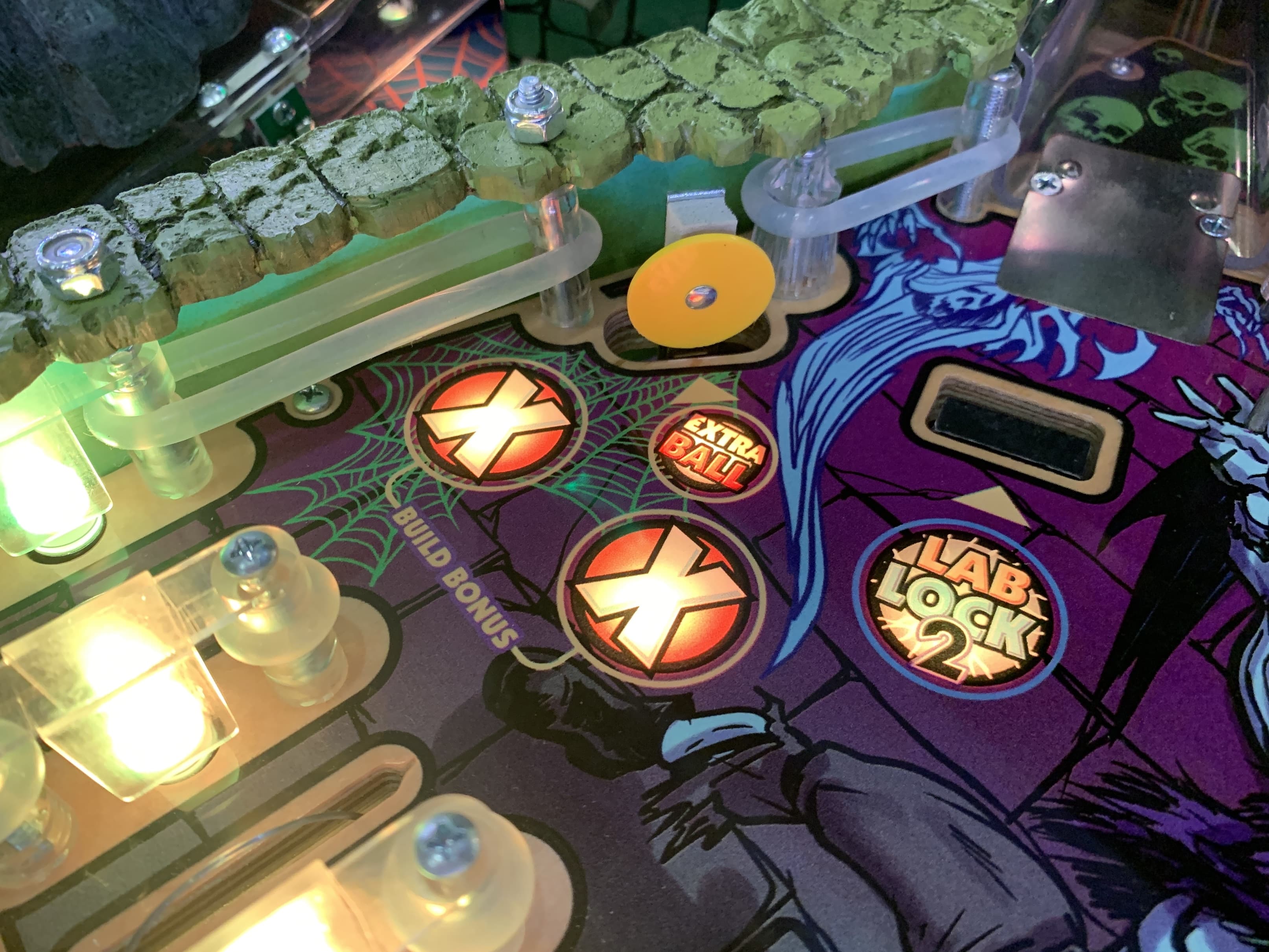 Pinball machine close-up with glowing lights and bonus markers