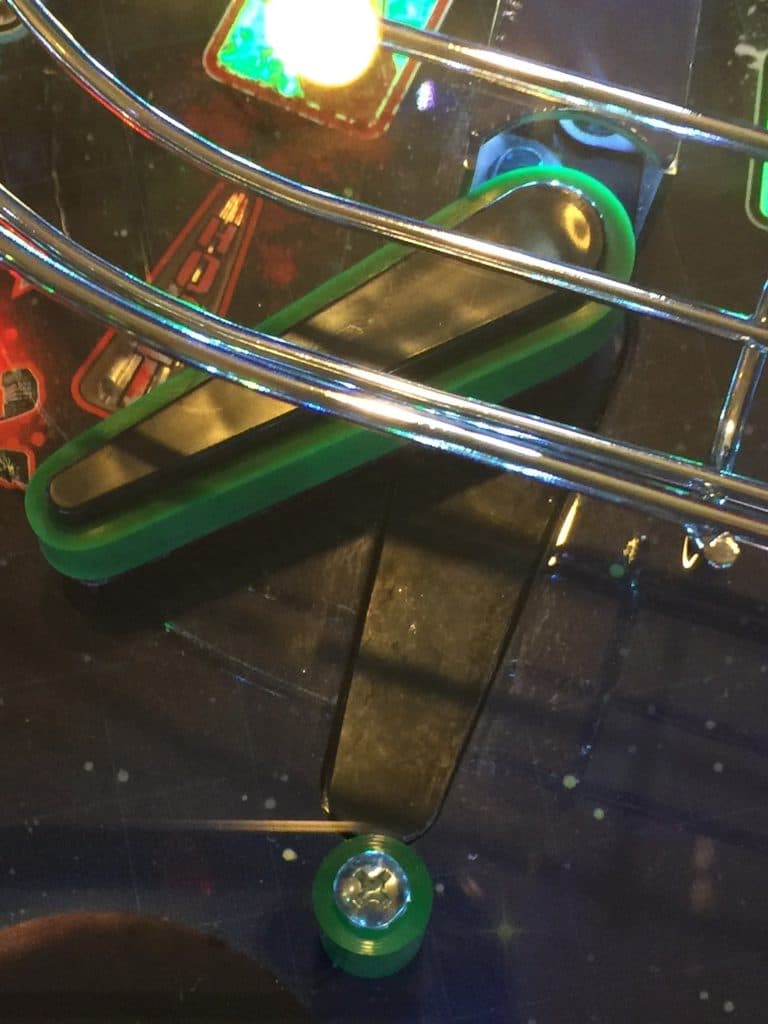 Pinball machine with metallic rails and colorful green and blue elements