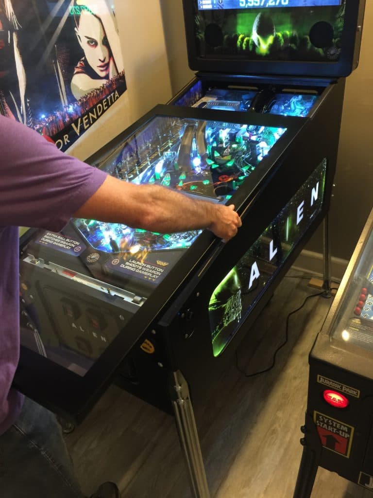 Alien-themed pinball machine with glowing green and blue lights