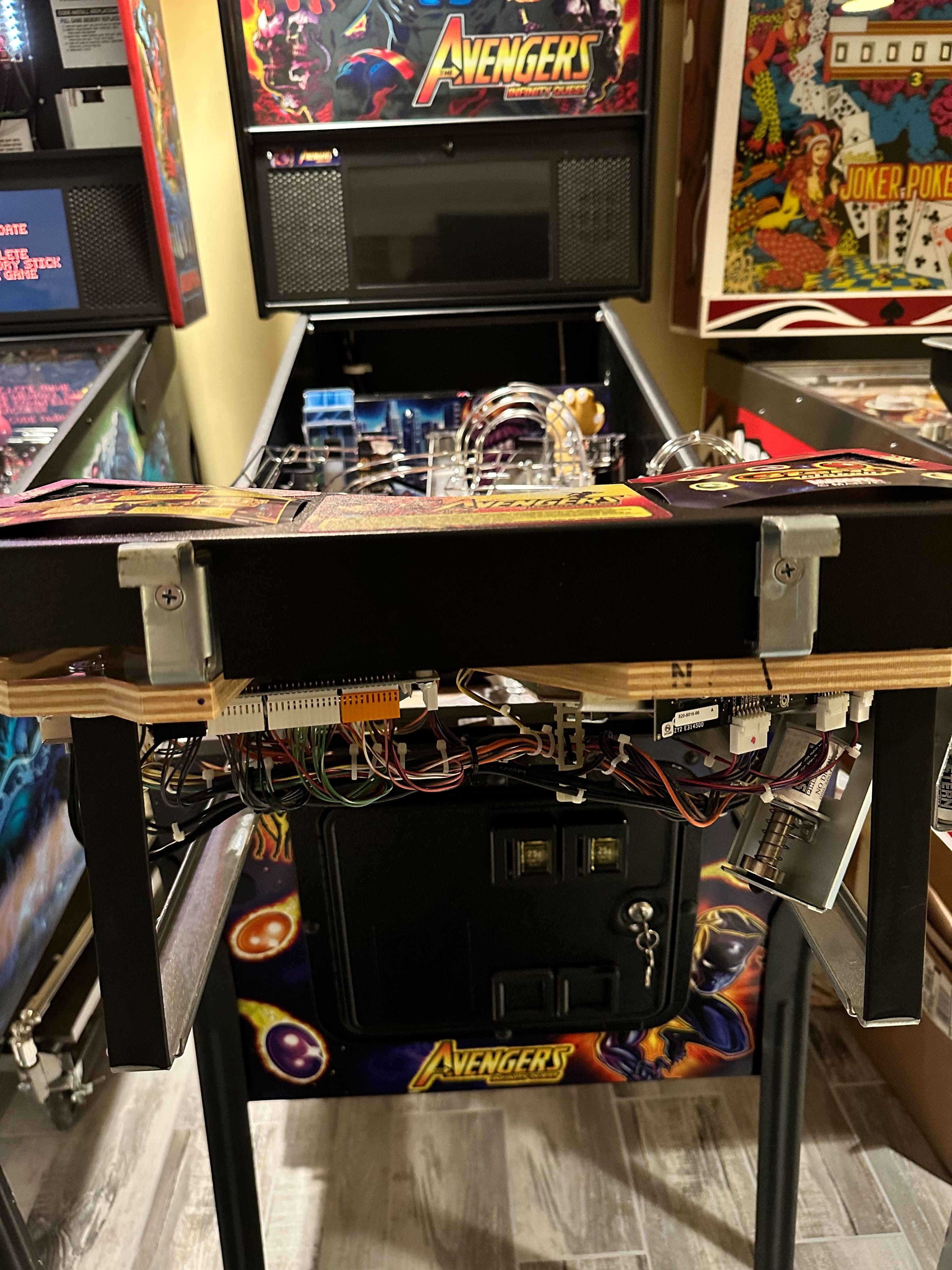 Avengers-themed pinball machine with open back panel showing internal electronics