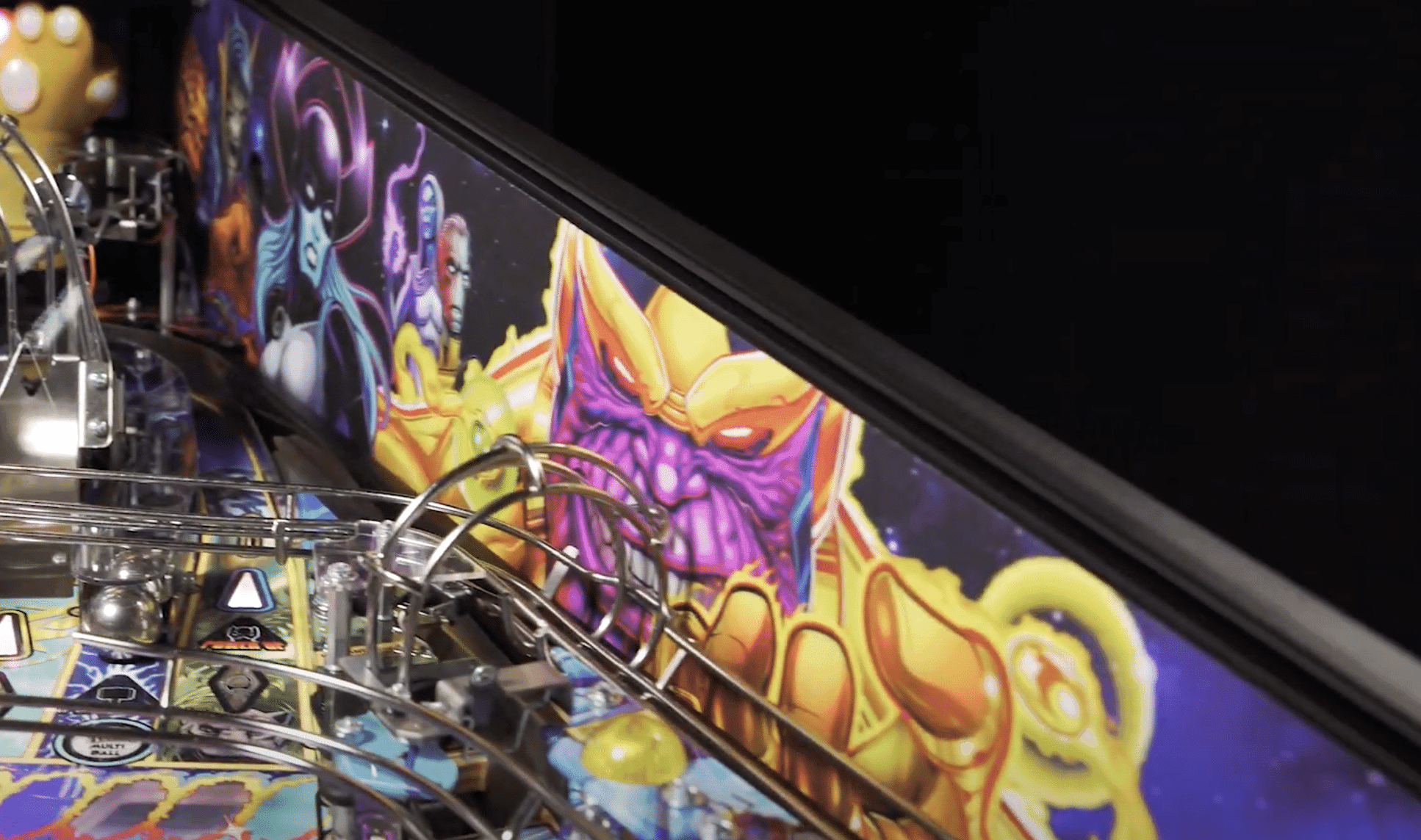 Colorful fantasy monster artwork on pinball machine backglass with mechanical elements