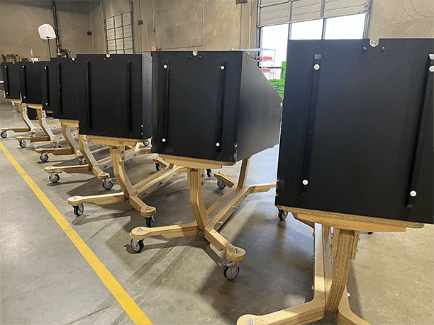 Row of black mobile privacy screens on wooden stands with wheels