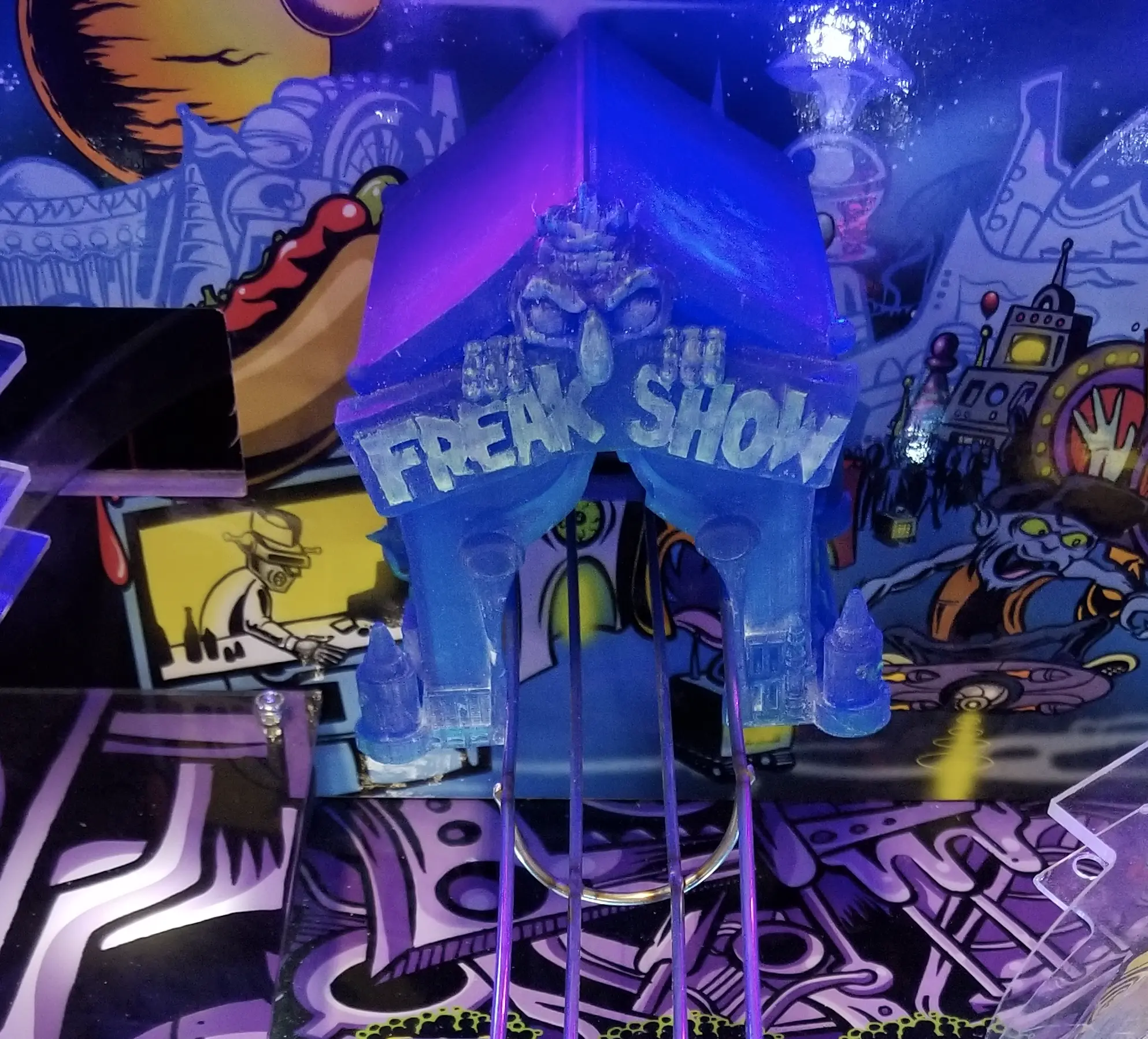 Colorful pinball machine with blue "Freak Show" sign and surreal background