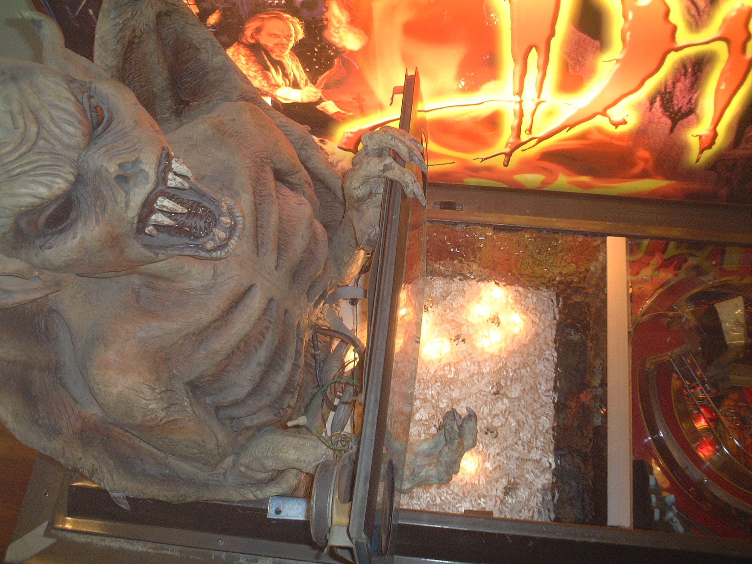 Large creature sculpture with fiery background in dimly lit exhibition