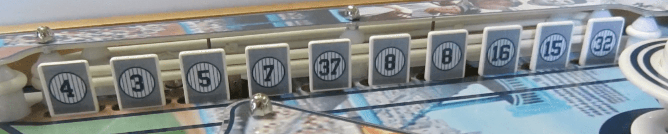 Yankees retired jersey number tiles displayed on a baseball-themed surface