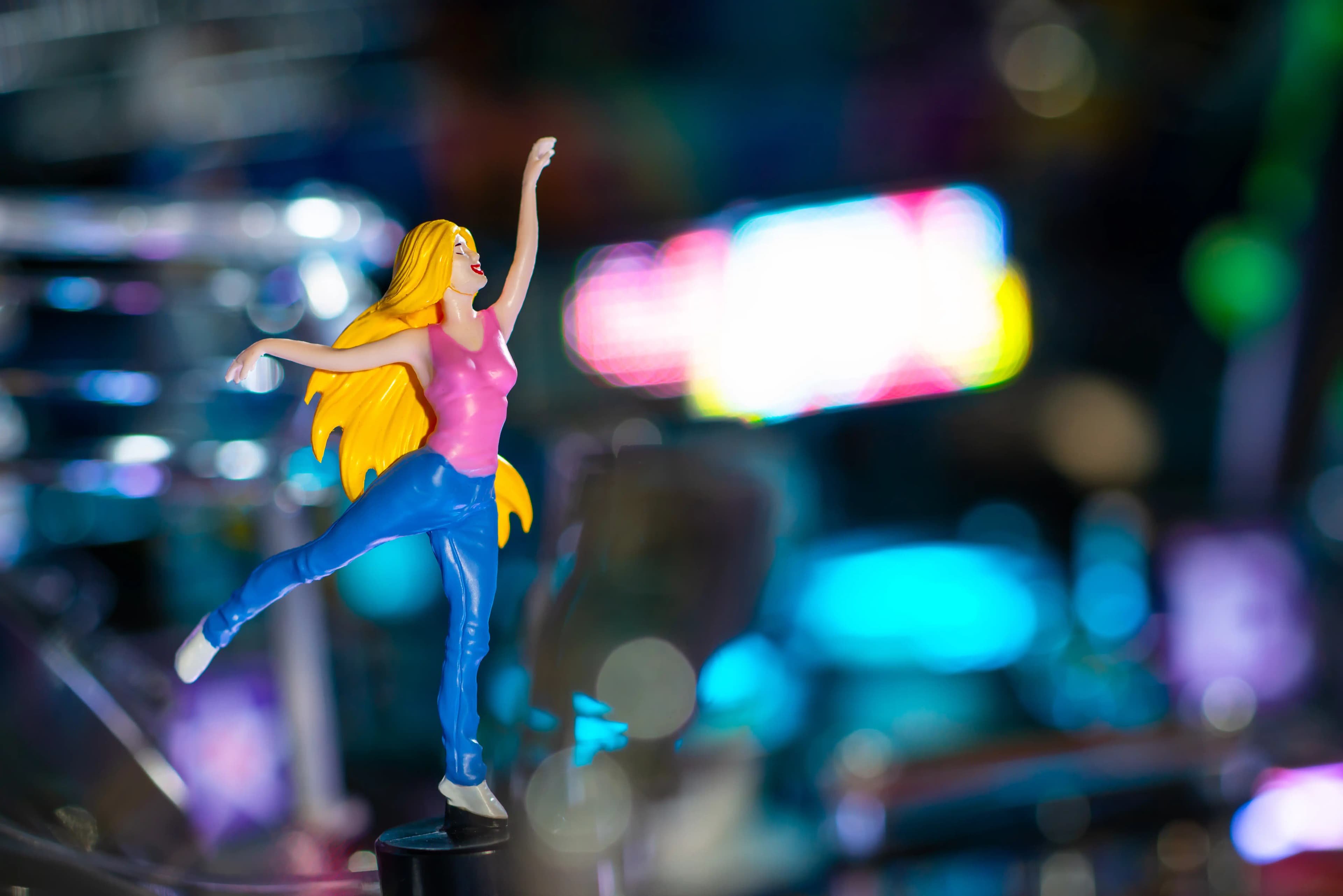 Colorful figurine of dancing woman with long yellow hair in dynamic pose