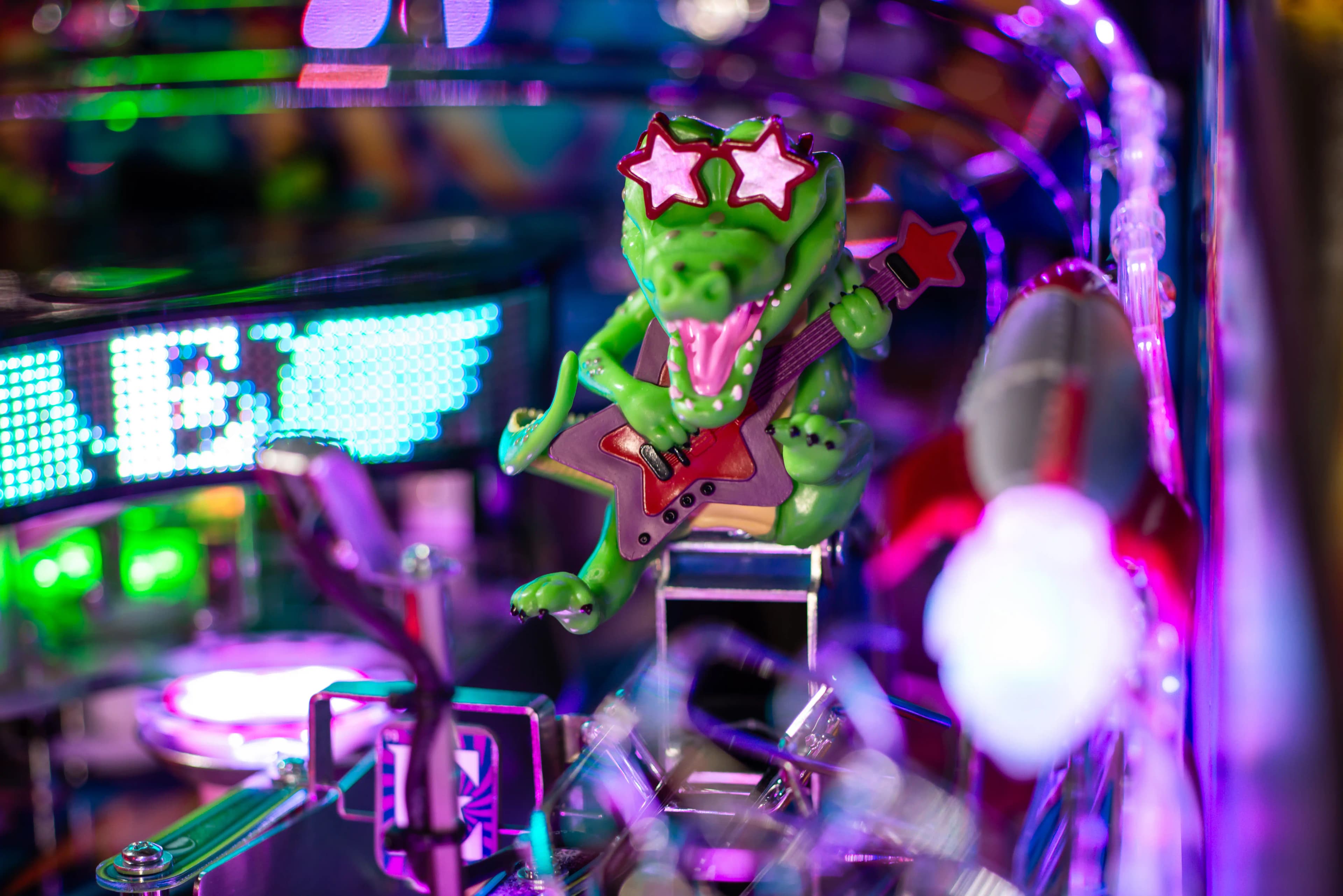 Green crocodile wearing star glasses playing electric guitar in neon setting