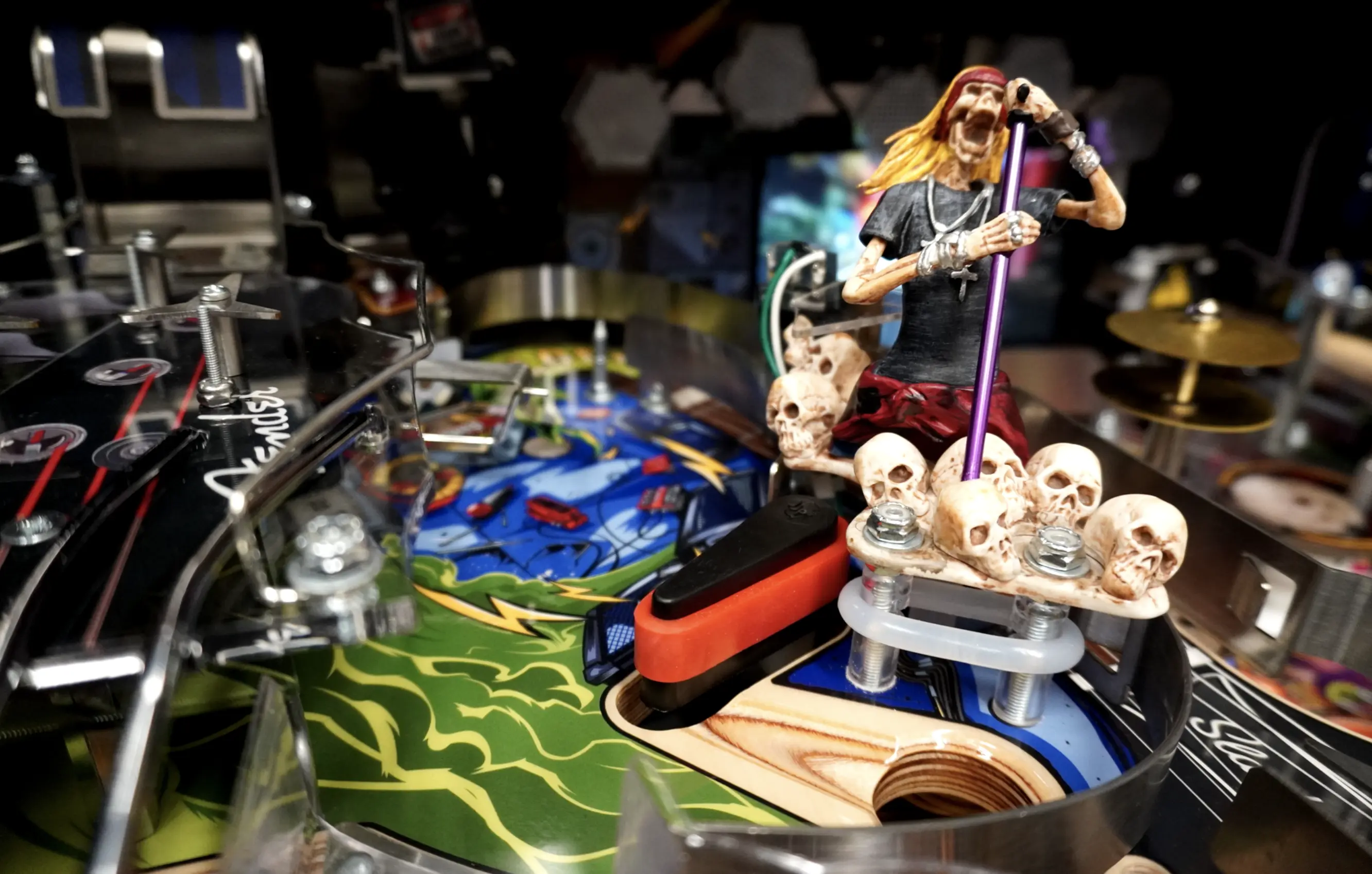 Rock musician figurine standing on skulls with colorful pinball machine background