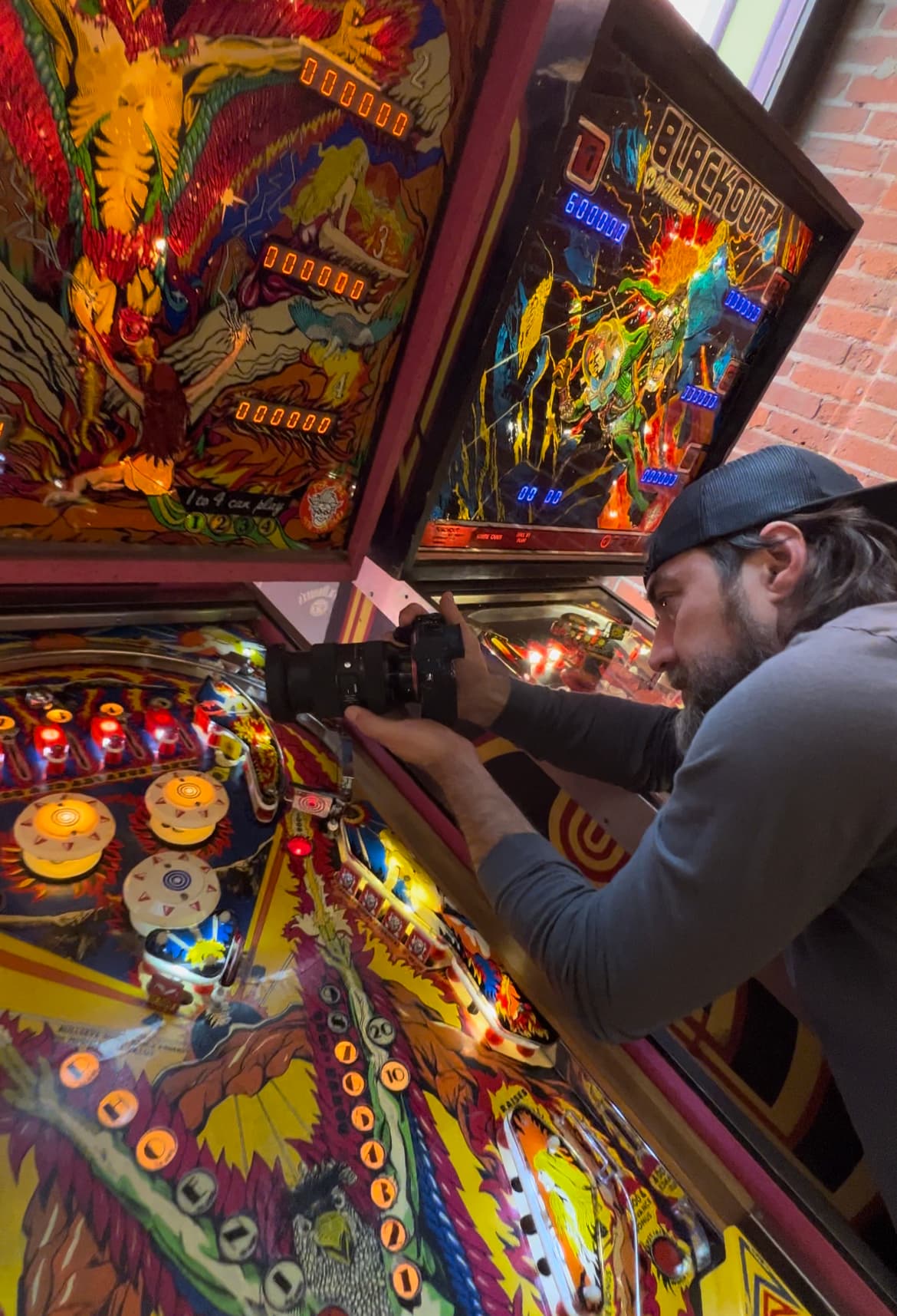 Player focusing intently on colorful vintage pinball machine with flashing lights