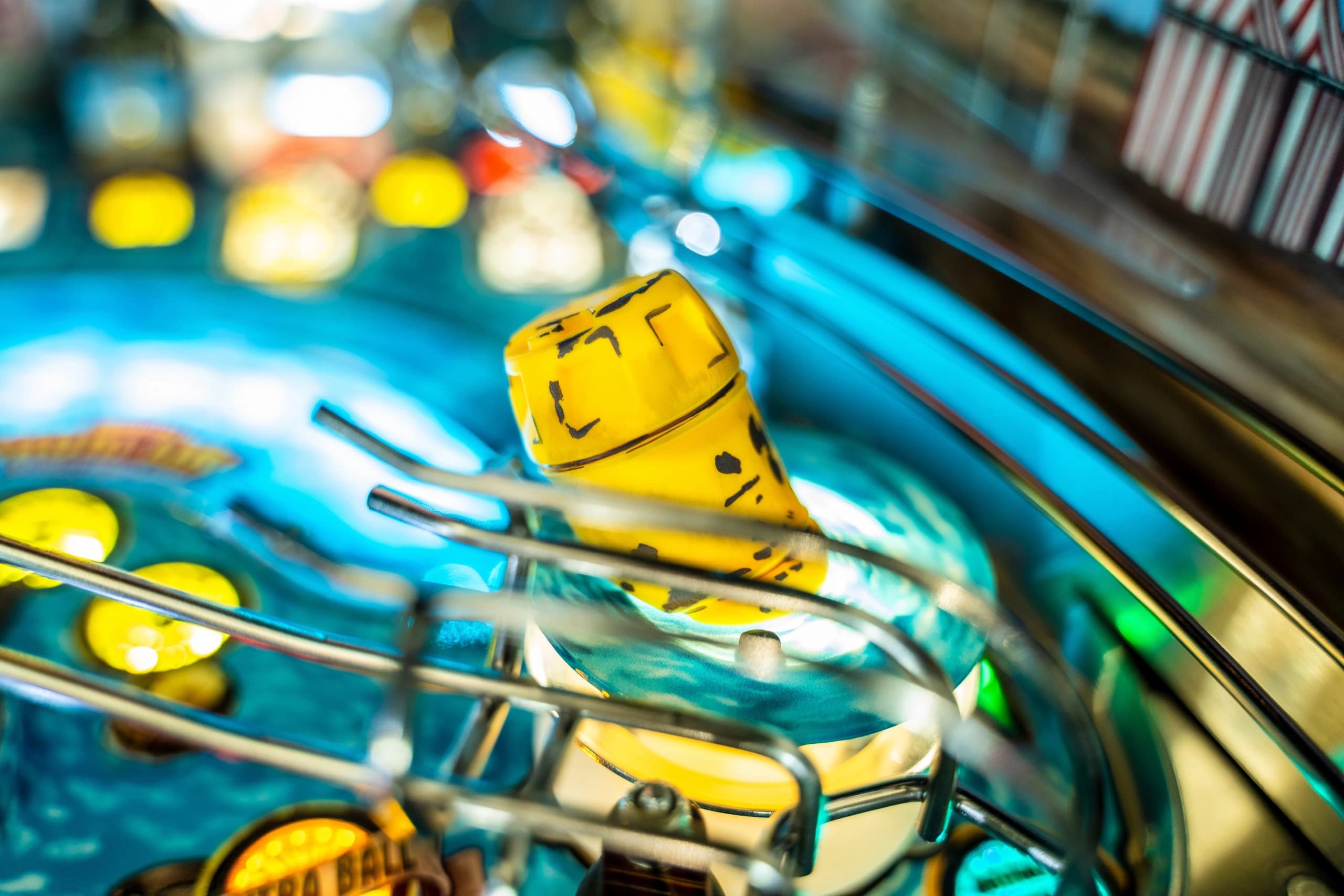 Yellow pinball bumper on vibrant blue playfield with blurred background