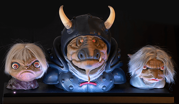 Three creepy dolls with horned helmet, glowing eyes, and unusual expressions