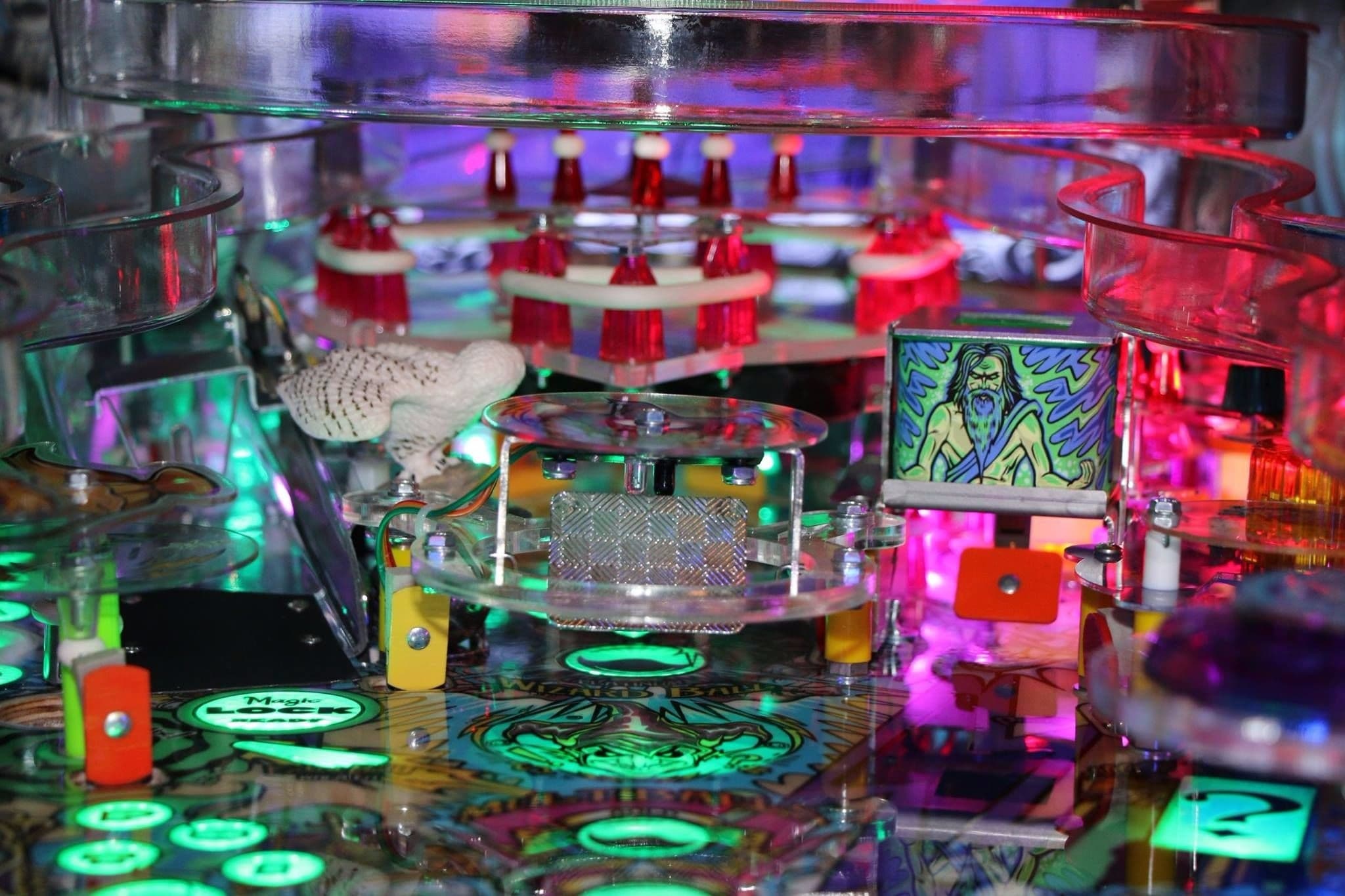 Colorful pinball machine with glowing green and red lights and artistic elements