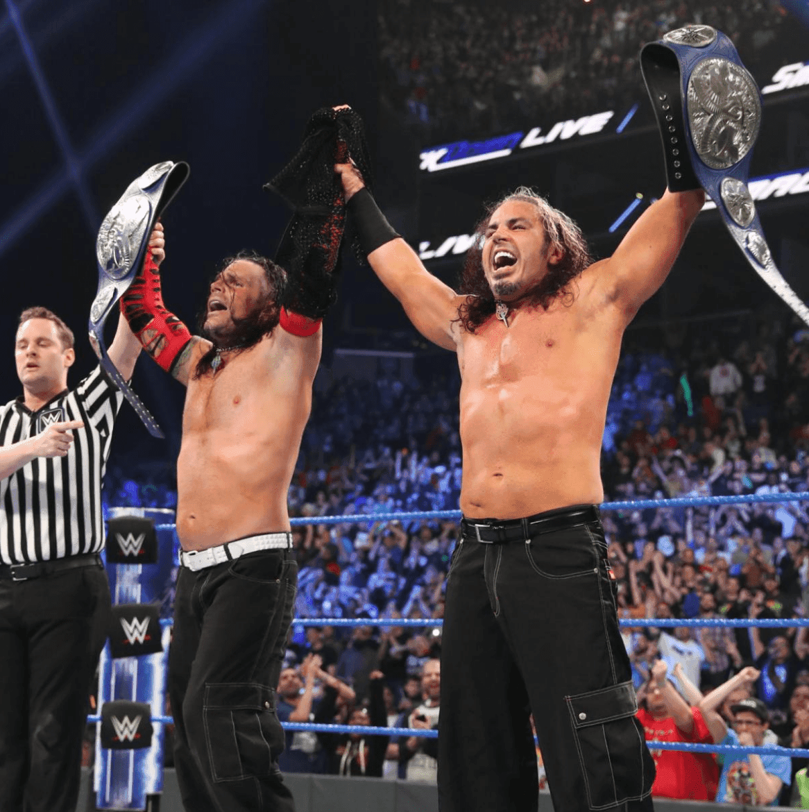 WWE wrestlers celebrating victory with championship belts raised