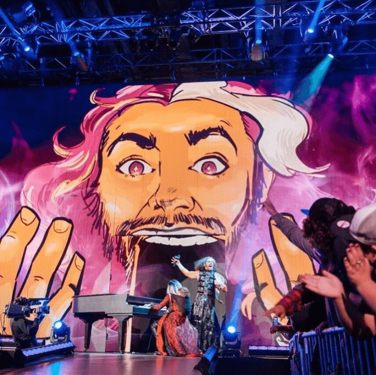 Theatrical stage with large animated cartoon face backdrop and performer