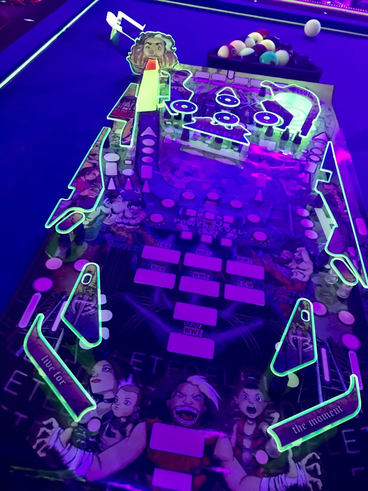 Neon-lit pinball machine with vibrant purple and green color scheme