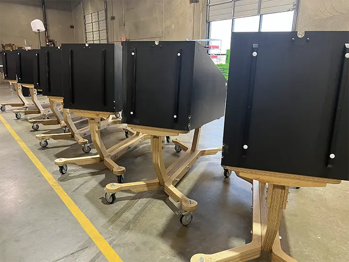 Row of black mobile privacy screens on wooden stands with wheels