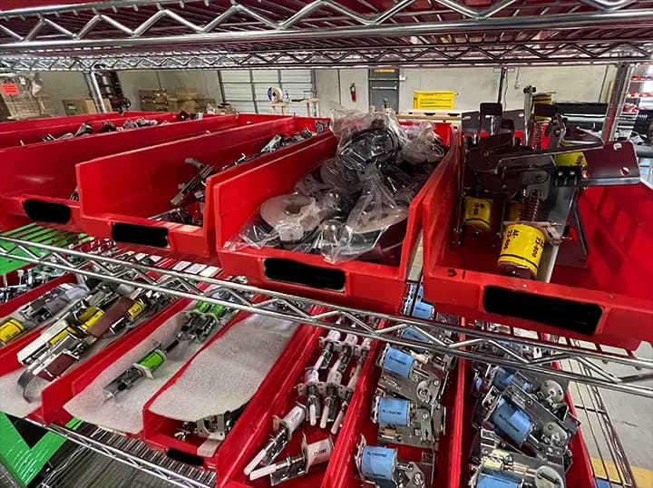 Red storage bins with mechanical parts and electrical components on shelves