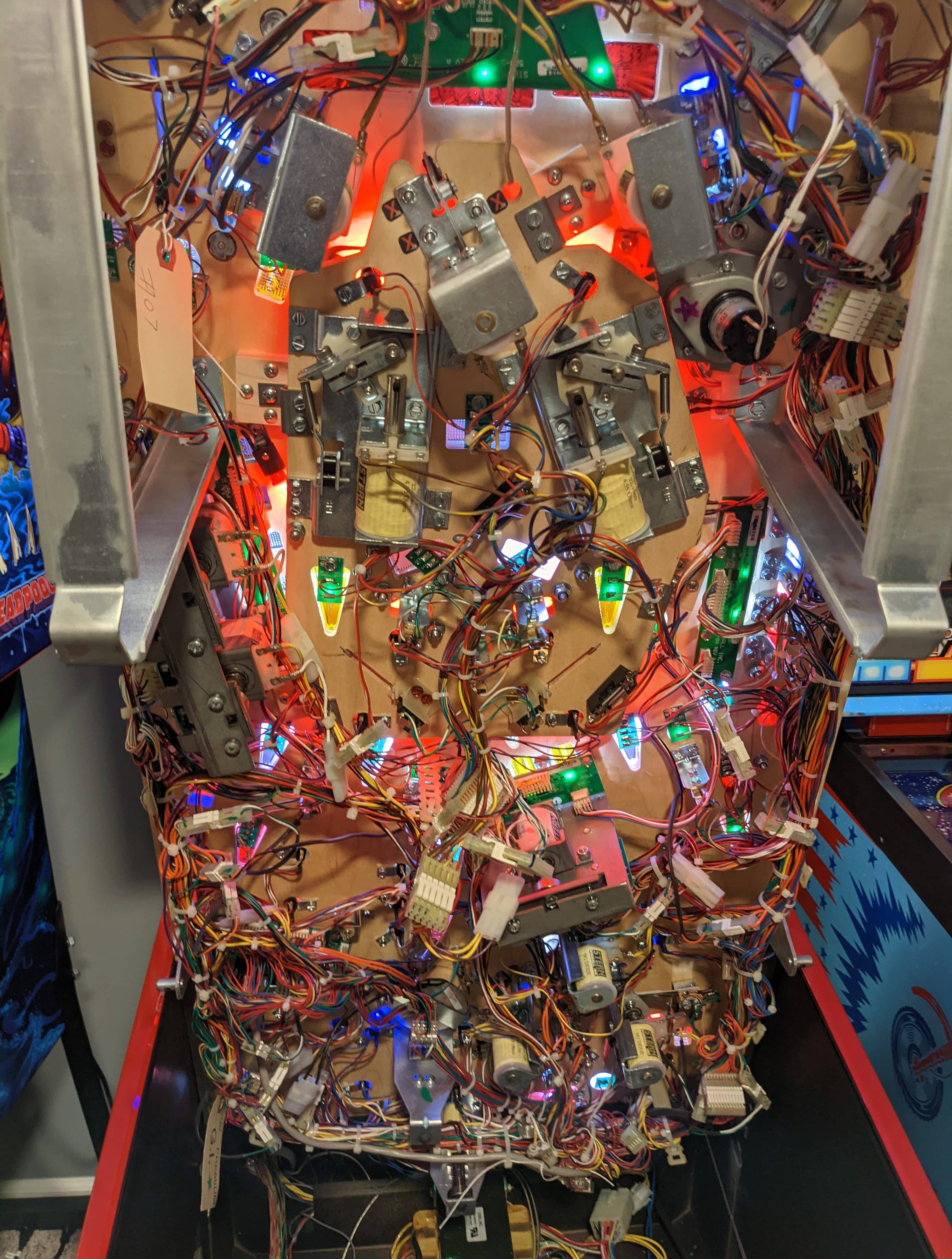 Intricate pinball machine internal electronics with colorful lights and complex wiring