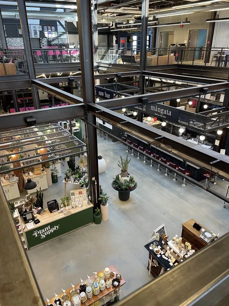 Multi-level indoor market with plant shop, bar, and various vendor stalls