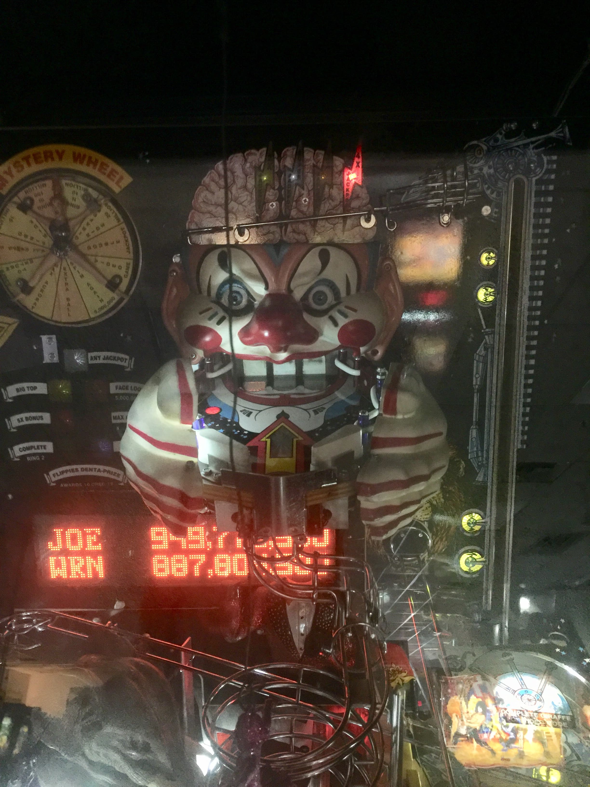 Creepy mechanical clown with digital display in dimly lit arcade machine