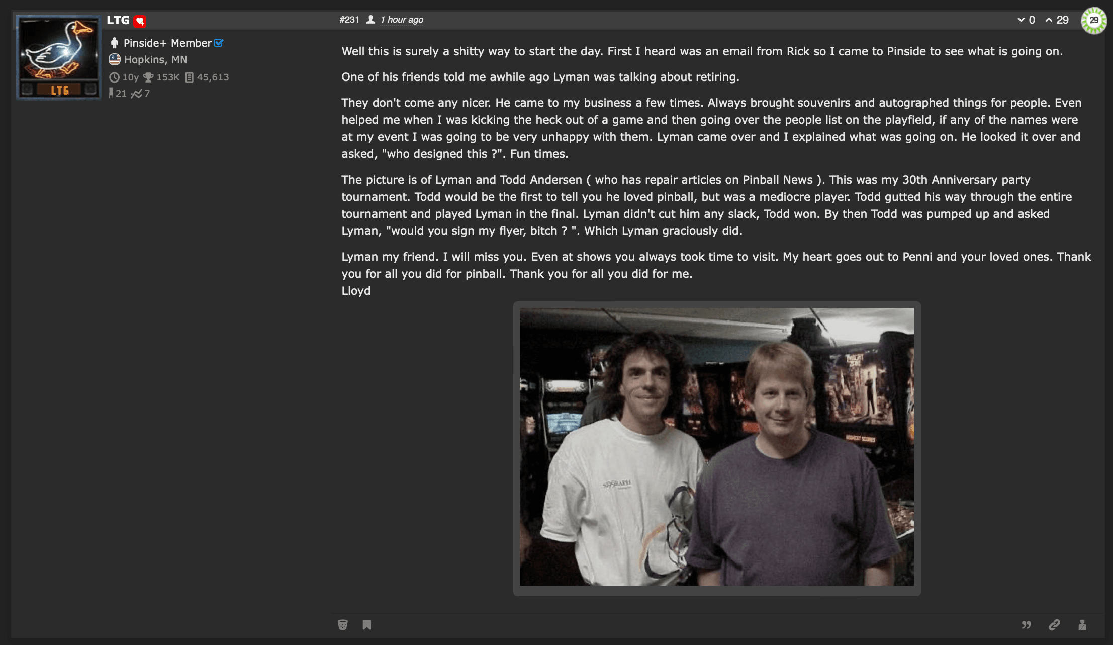 Two men standing together in front of pinball machines at an event