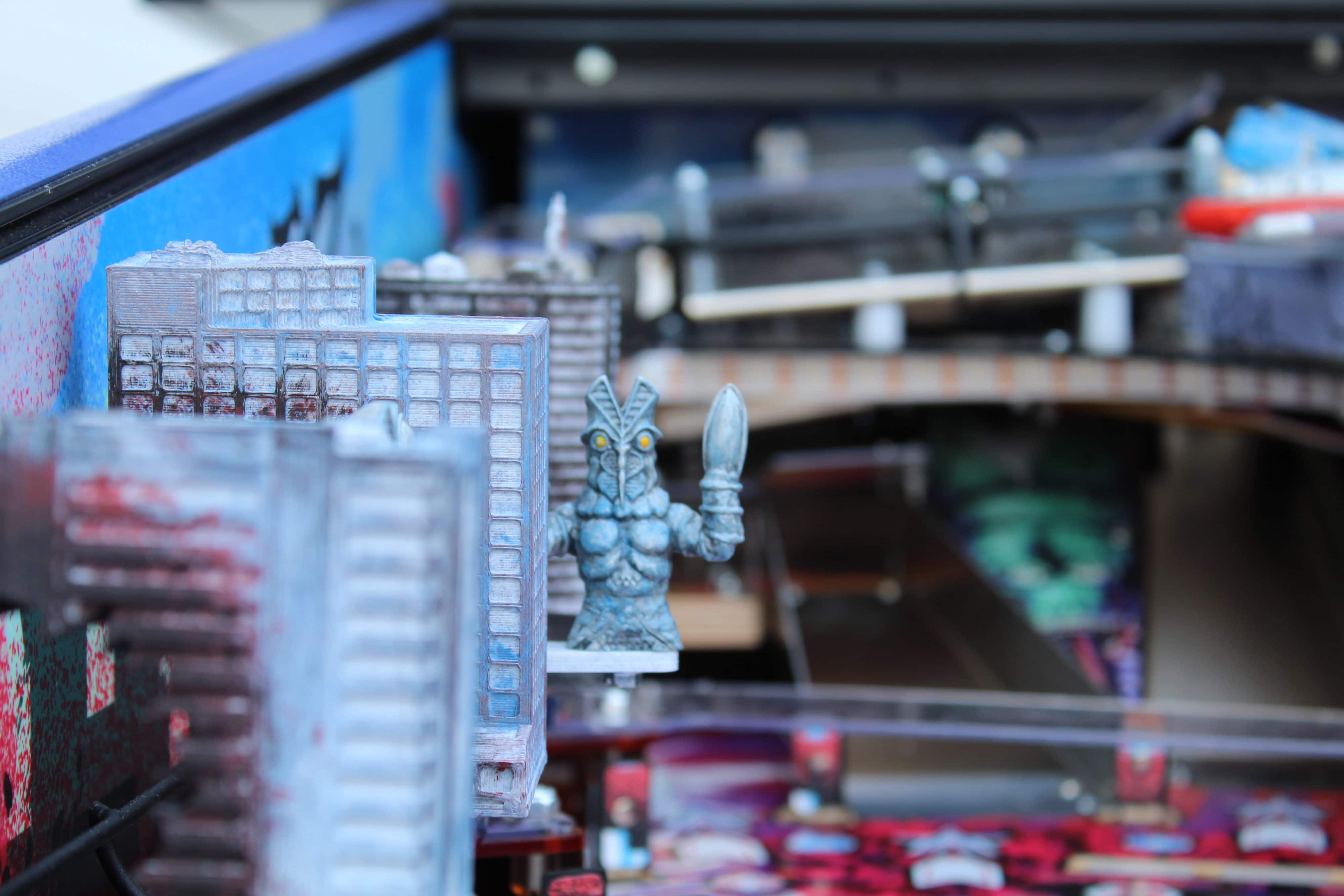 Miniature buildings and alien-like figurine on a detailed workshop shelf