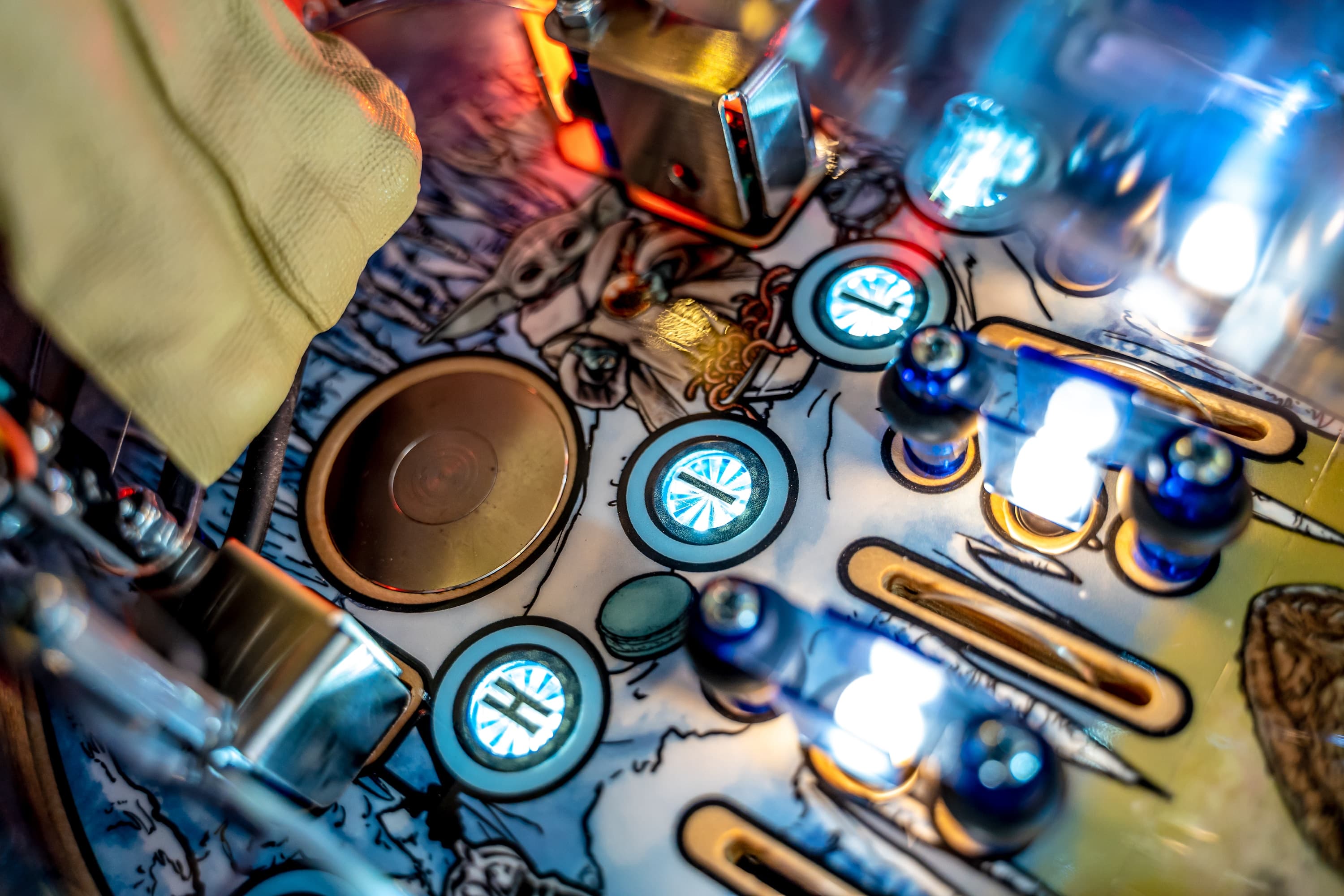 Colorful pinball machine detail with glowing buttons and metallic components