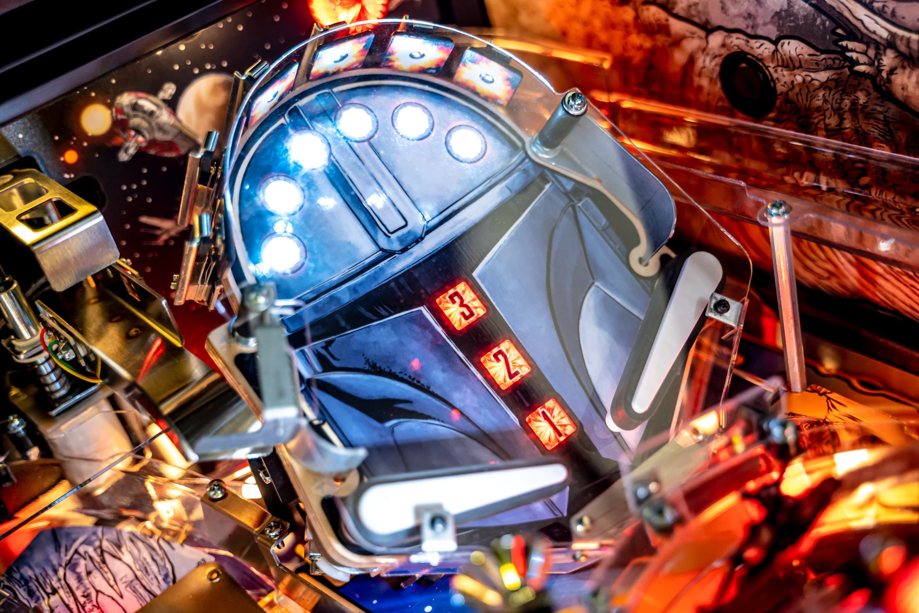 Close-up of illuminated pinball machine with robotic design and glowing lights