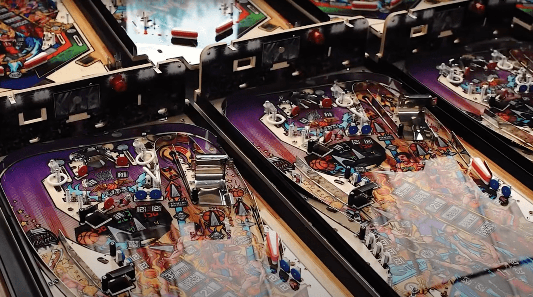 Close-up of colorful vintage pinball machines with intricate playfield designs