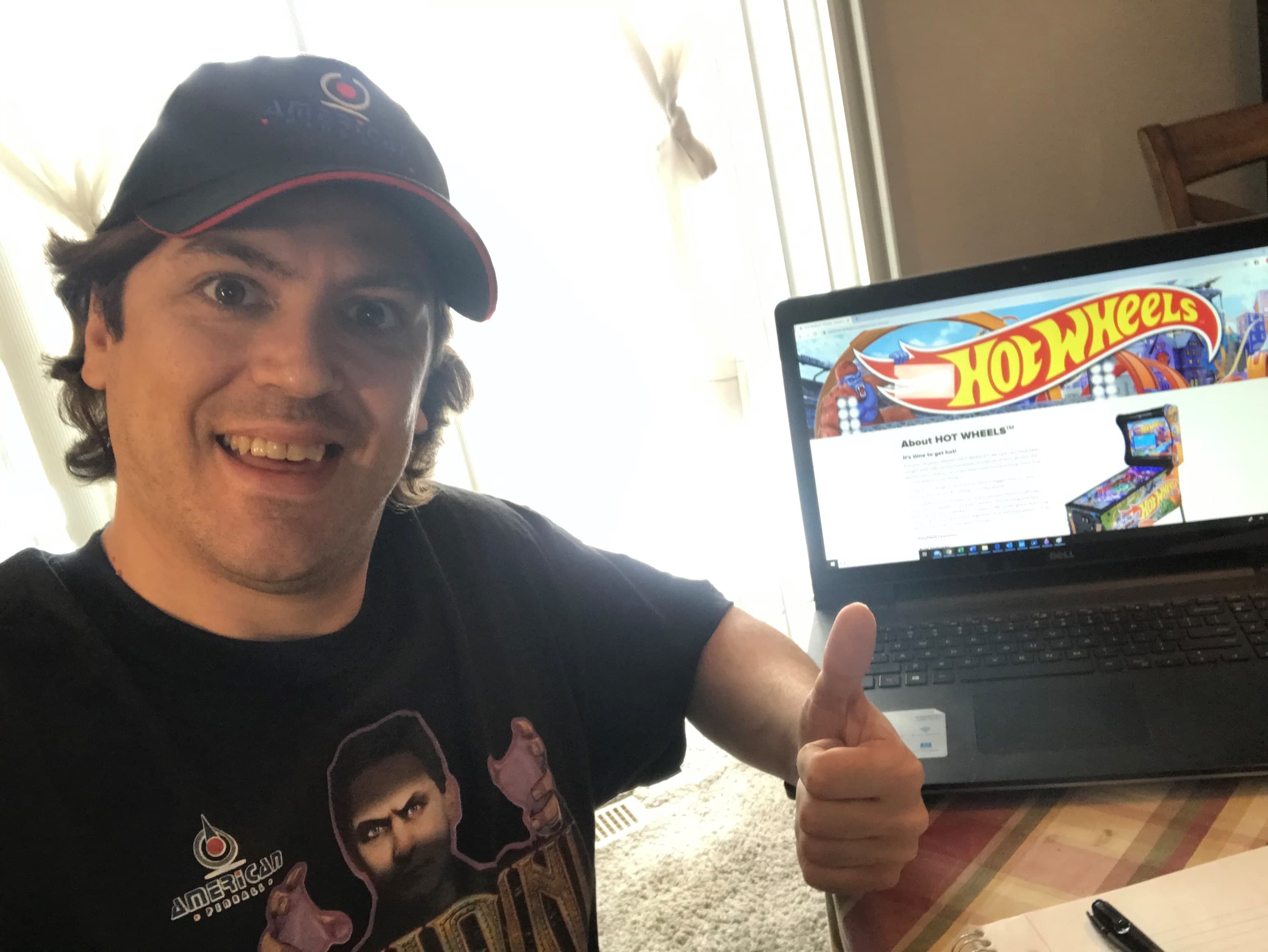 Smiling person with Hot Wheels website on laptop giving thumbs up