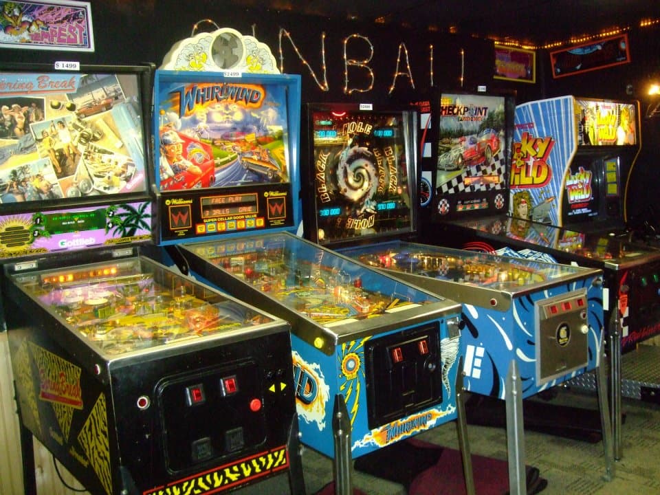 Vintage pinball machines lined up in an arcade with colorful artwork