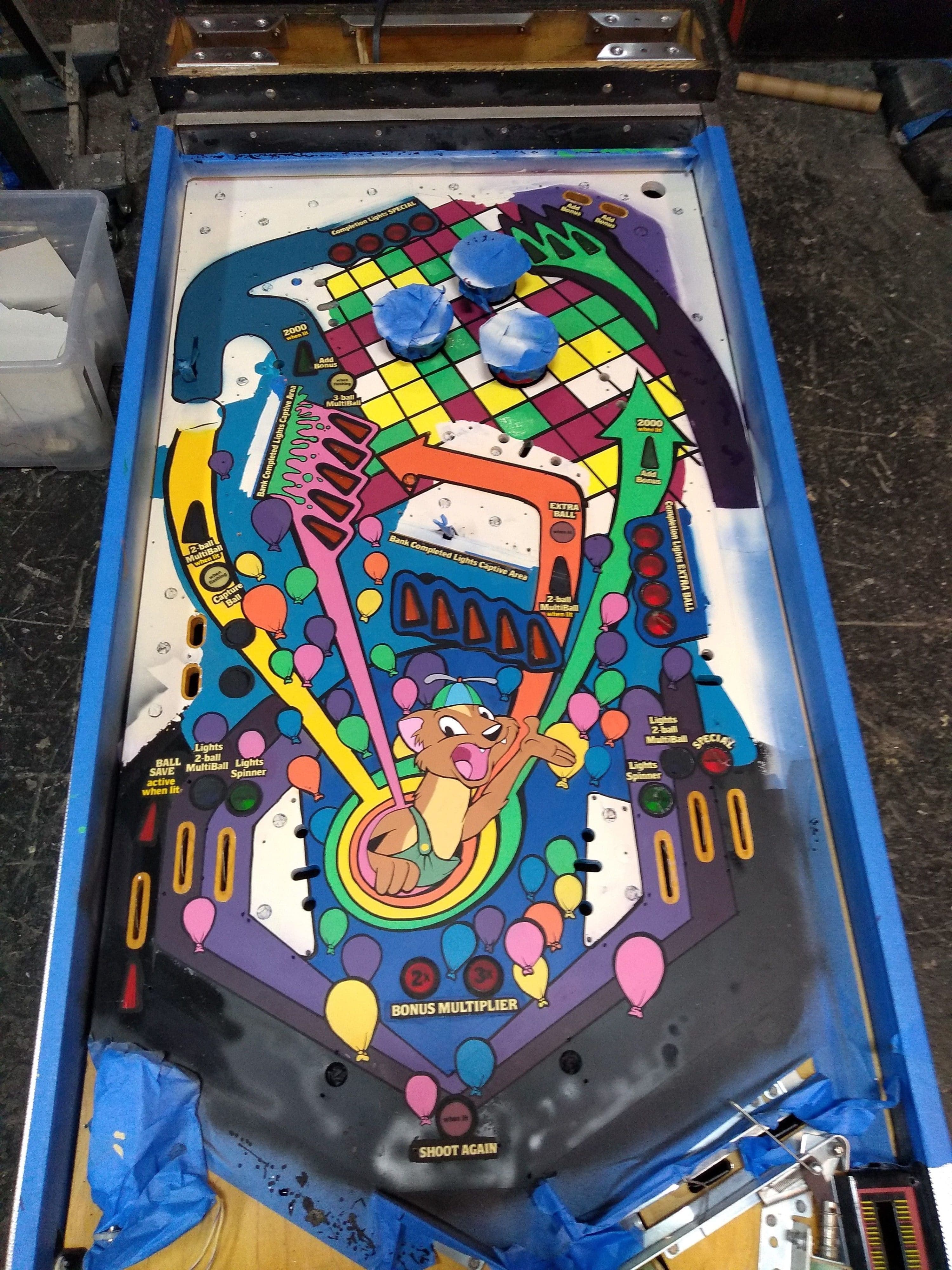 Colorful pinball machine playfield with cartoon character and balloons