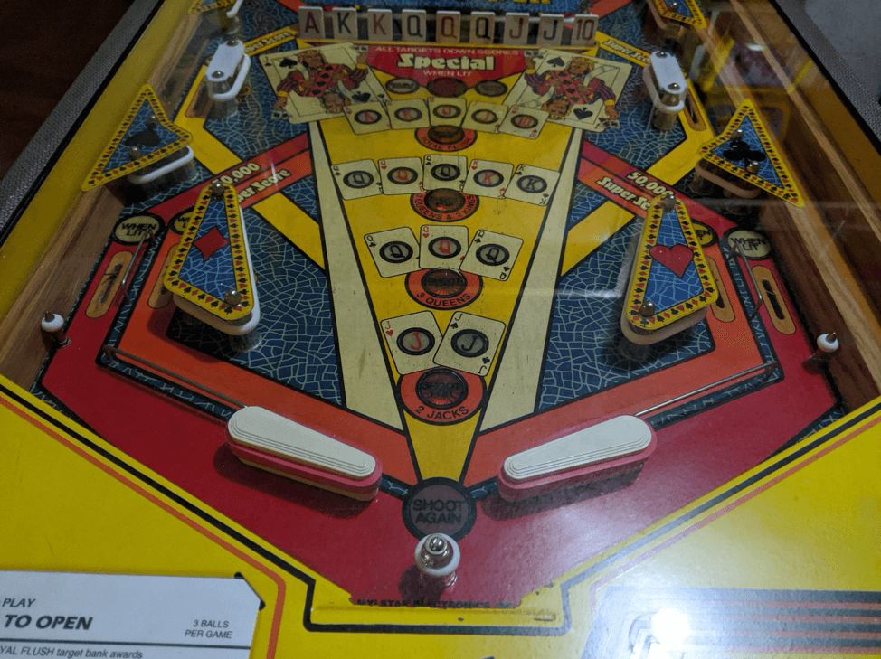 Vintage pinball machine playfield with colorful graphics and flippers
