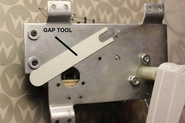 Metal gap tool with white lever mounted on mechanical bracket
