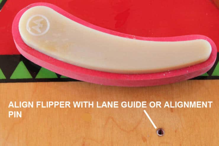 Pink and beige flipper with alignment pin on wooden surface